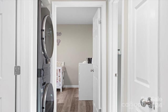 washroom with hardwood / wood-style flooring and stacked washing maching and dryer