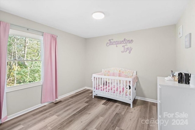 bedroom featuring light hardwood / wood-style flooring and a nursery area