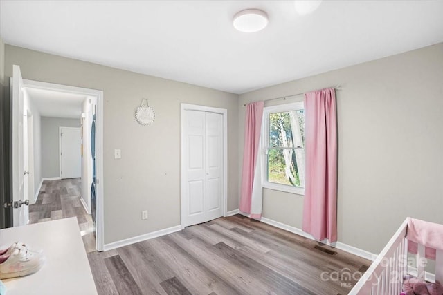 bedroom with a crib, light hardwood / wood-style floors, and a closet