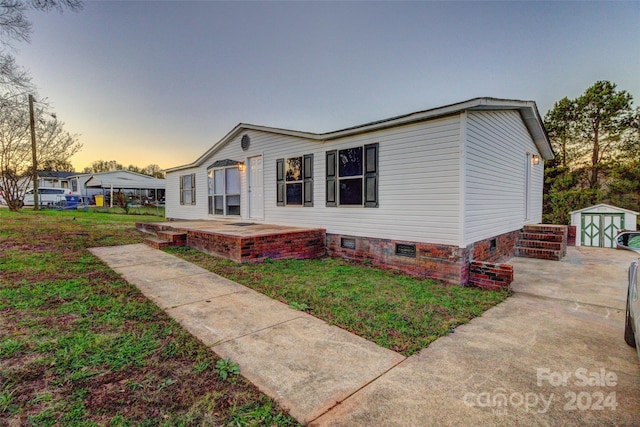 view of front of home with a yard and a storage unit