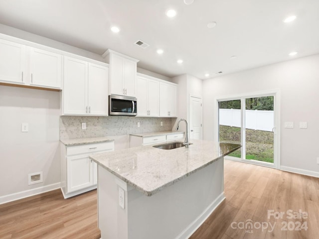 kitchen featuring white cabinetry, sink, and an island with sink