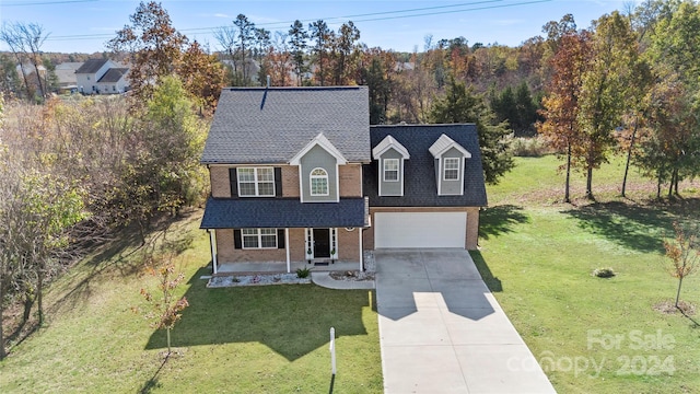 view of front property featuring covered porch, a front yard, and a garage