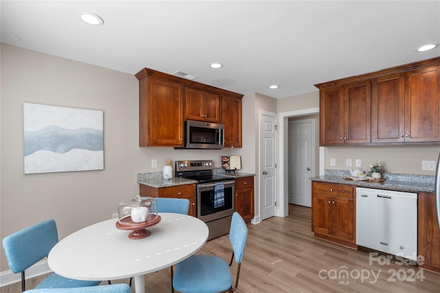 kitchen with light stone countertops, stainless steel appliances, and light hardwood / wood-style flooring