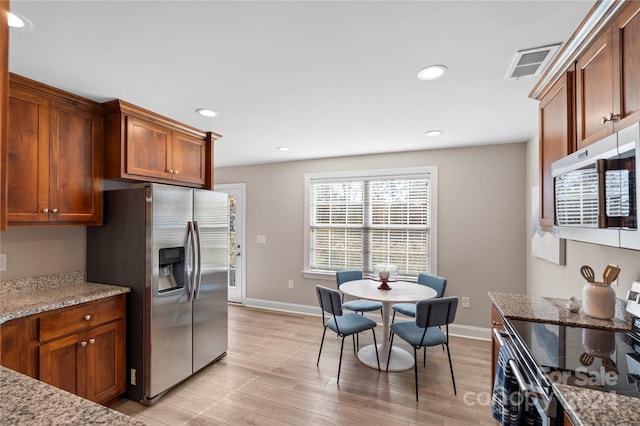 kitchen with light stone counters, light hardwood / wood-style floors, and appliances with stainless steel finishes