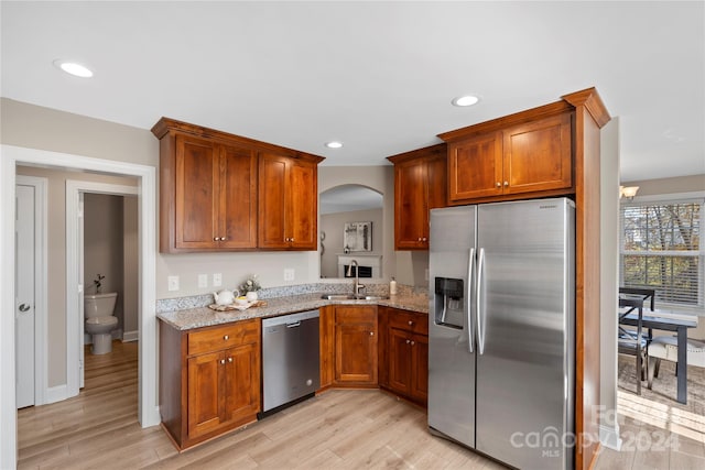 kitchen with light stone countertops, sink, appliances with stainless steel finishes, and light hardwood / wood-style flooring