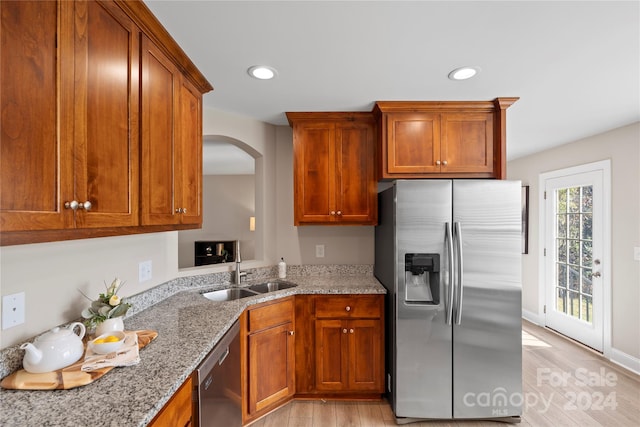 kitchen featuring light stone countertops, sink, light wood-type flooring, and appliances with stainless steel finishes