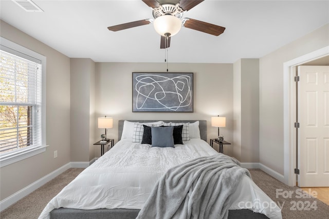 carpeted bedroom featuring multiple windows and ceiling fan