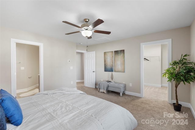 bedroom with light colored carpet, ceiling fan, a spacious closet, connected bathroom, and a closet