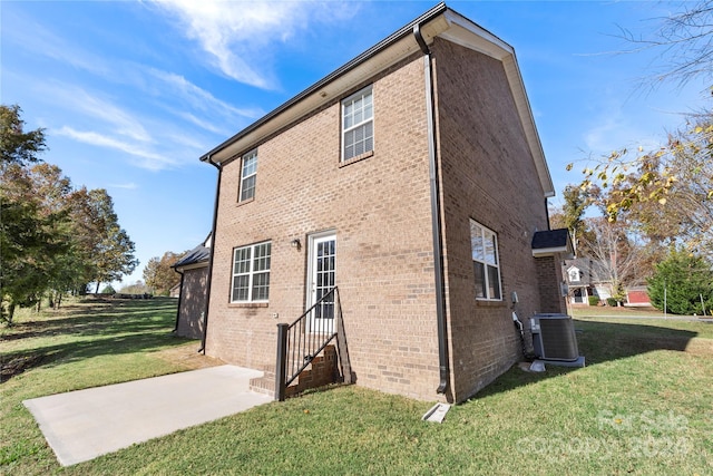 rear view of house with central air condition unit and a lawn