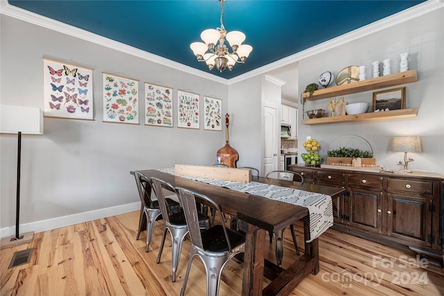 dining area featuring crown molding, light hardwood / wood-style floors, and an inviting chandelier