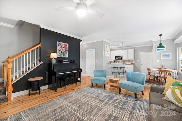 living room featuring ceiling fan, ornamental molding, and hardwood / wood-style flooring