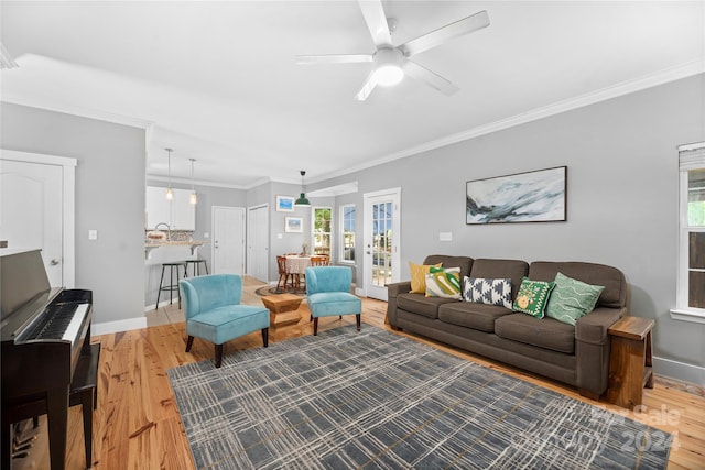 living room featuring ceiling fan, crown molding, and light hardwood / wood-style floors