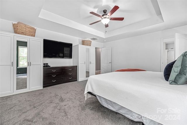 carpeted bedroom with ceiling fan and a tray ceiling