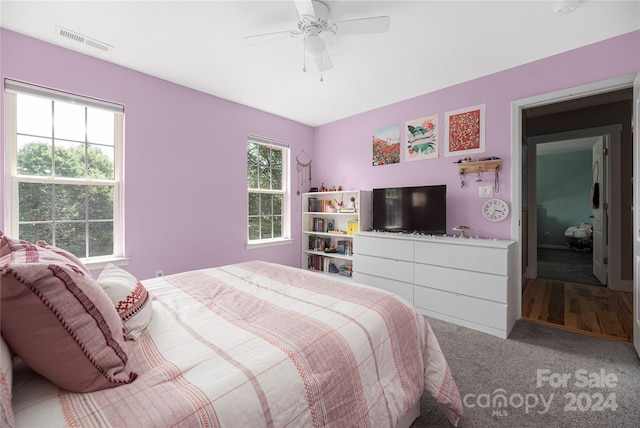 carpeted bedroom featuring multiple windows and ceiling fan