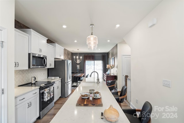 kitchen featuring white cabinetry, stainless steel appliances, light stone counters, dark hardwood / wood-style flooring, and decorative light fixtures