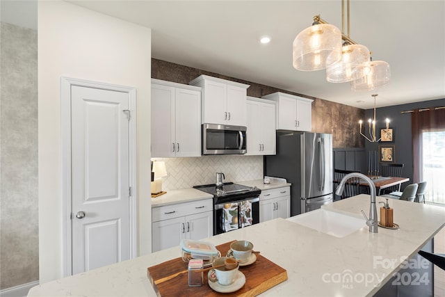 kitchen featuring white cabinets, pendant lighting, stainless steel appliances, and sink