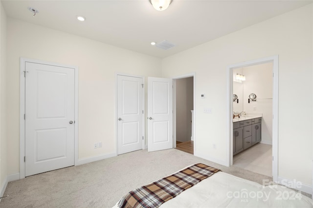 bedroom featuring light carpet and ensuite bath