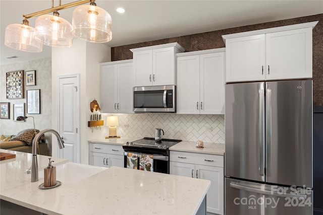 kitchen featuring pendant lighting, stainless steel appliances, and white cabinetry