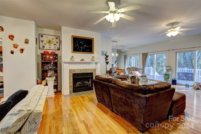 living room with a tile fireplace, light hardwood / wood-style flooring, and ceiling fan