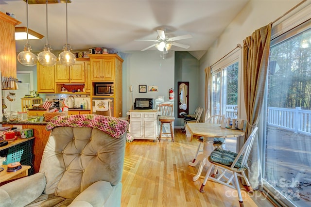 kitchen featuring stainless steel appliances, ceiling fan, sink, pendant lighting, and light hardwood / wood-style flooring