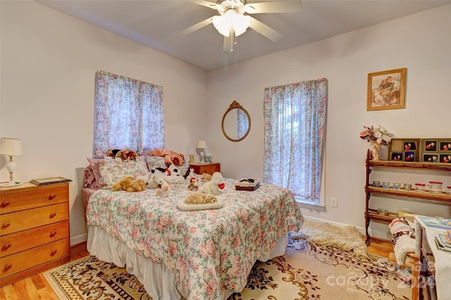 bedroom with multiple windows, ceiling fan, and light wood-type flooring