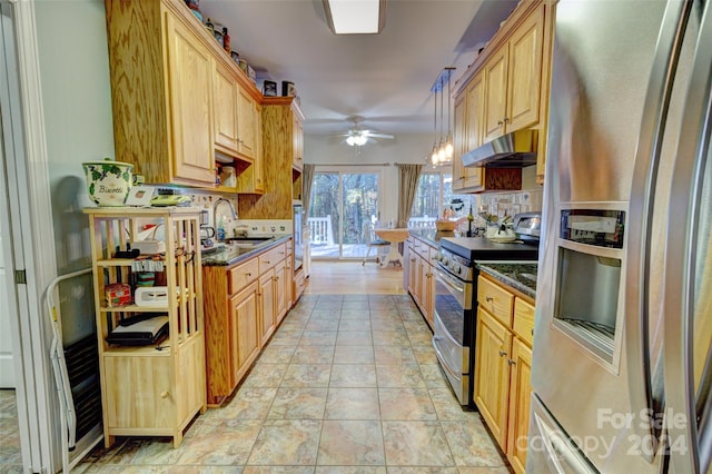 kitchen featuring stainless steel appliances, ceiling fan, sink, dark stone countertops, and hanging light fixtures