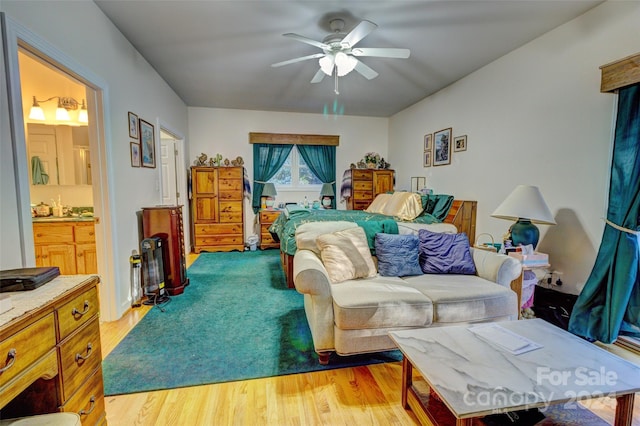 bedroom with connected bathroom, light hardwood / wood-style flooring, and ceiling fan