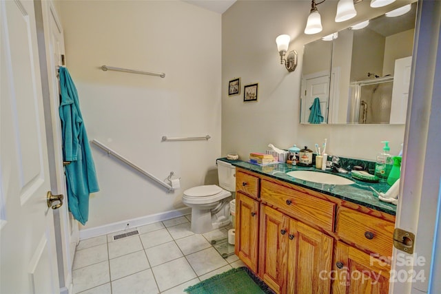 bathroom with tile patterned flooring, vanity, toilet, and a shower with shower door