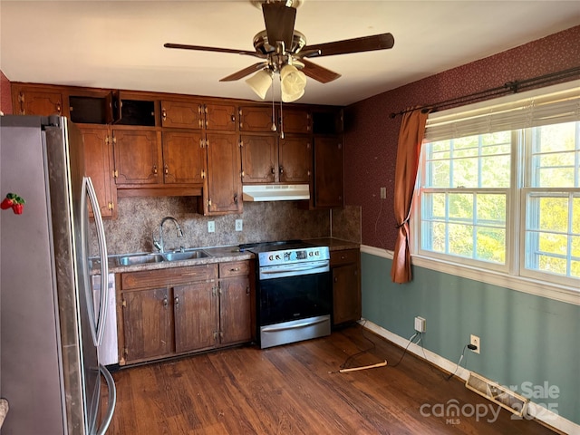 kitchen with appliances with stainless steel finishes, dark wood-type flooring, sink, backsplash, and ceiling fan