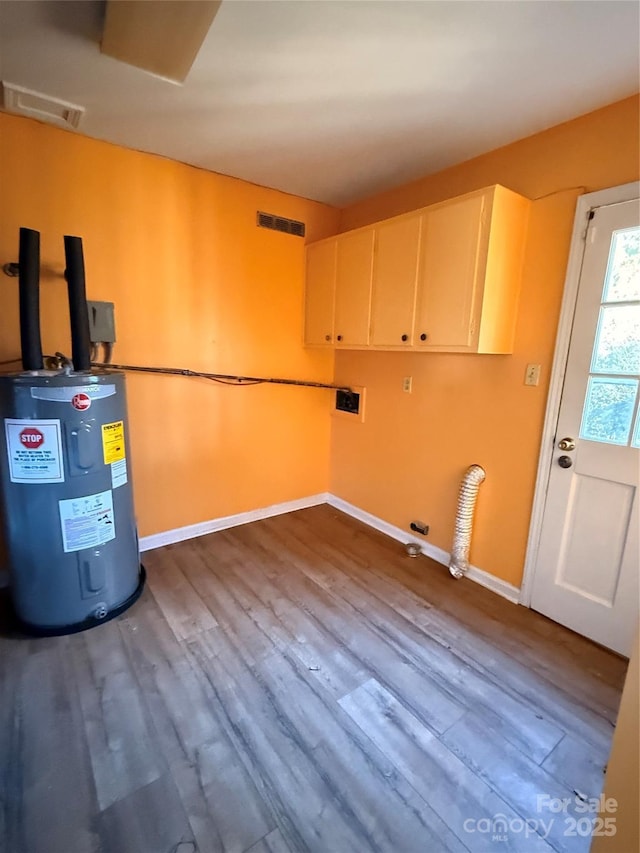 clothes washing area featuring hardwood / wood-style flooring, cabinets, water heater, and hookup for a gas dryer