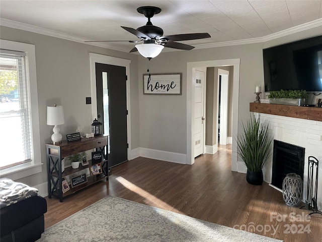 living room featuring crown molding, a fireplace, ceiling fan, and dark wood-type flooring