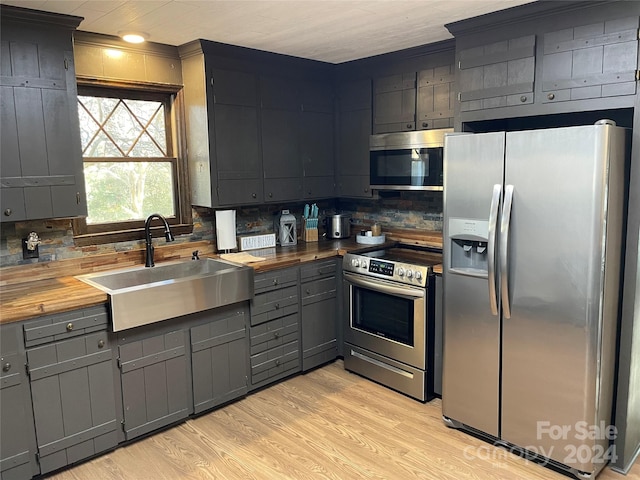 kitchen with sink, wood counters, light hardwood / wood-style flooring, decorative backsplash, and appliances with stainless steel finishes