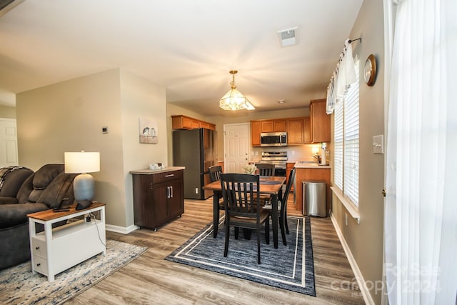 dining space featuring sink, an inviting chandelier, and light wood-type flooring