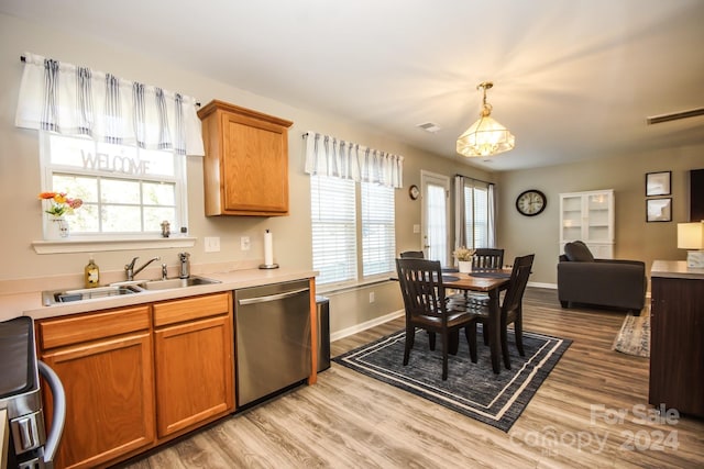 kitchen with sink, hanging light fixtures, stainless steel appliances, and light wood-type flooring