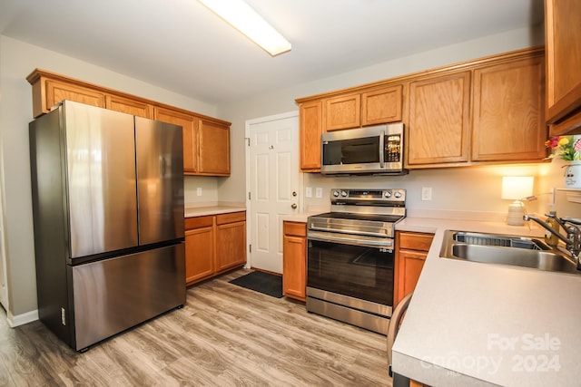 kitchen featuring sink, appliances with stainless steel finishes, and light hardwood / wood-style flooring