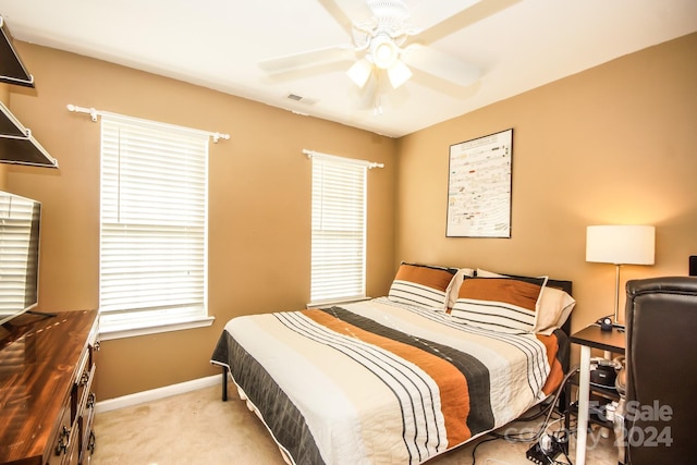 bedroom with multiple windows, ceiling fan, and light colored carpet