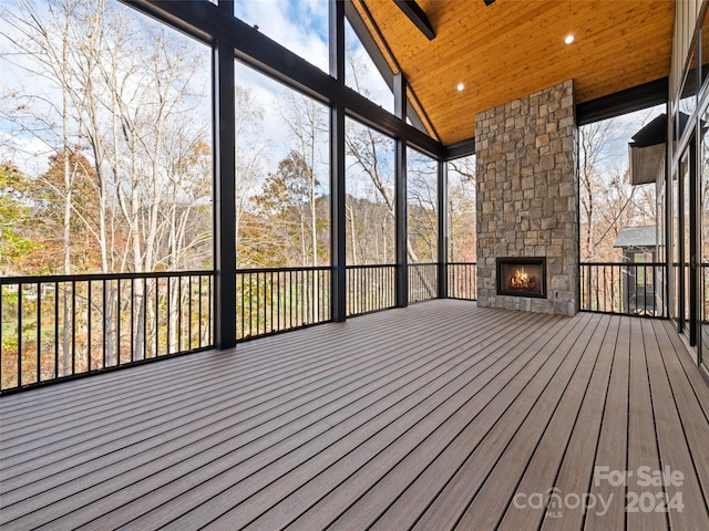 unfurnished sunroom with an outdoor stone fireplace, lofted ceiling, a healthy amount of sunlight, and wood ceiling