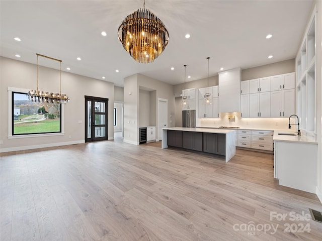 kitchen with light hardwood / wood-style flooring, white cabinets, hanging light fixtures, and stainless steel fridge