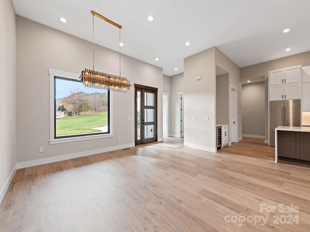 unfurnished living room with a chandelier and light hardwood / wood-style floors