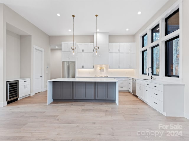 kitchen with white cabinets, light wood-type flooring, stainless steel appliances, and wine cooler