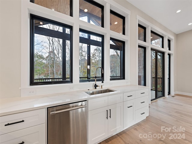 kitchen with white cabinetry, light stone countertops, sink, stainless steel dishwasher, and light wood-type flooring