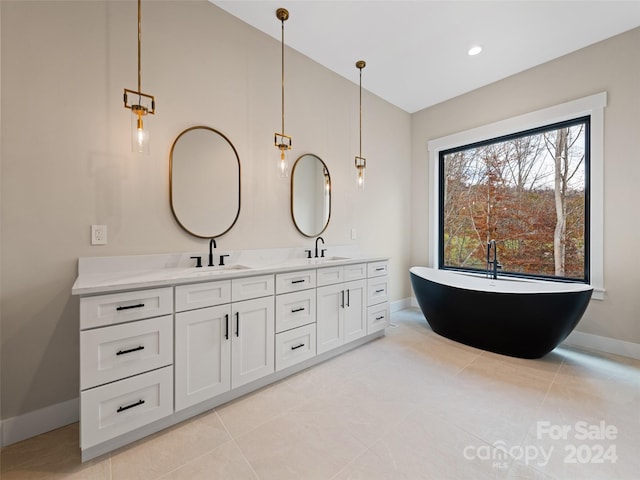 bathroom with a washtub, vanity, and tile patterned flooring