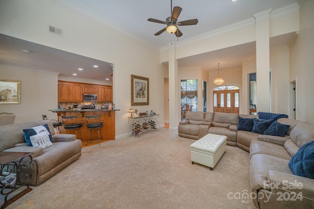 living room with ceiling fan, crown molding, light carpet, and a high ceiling