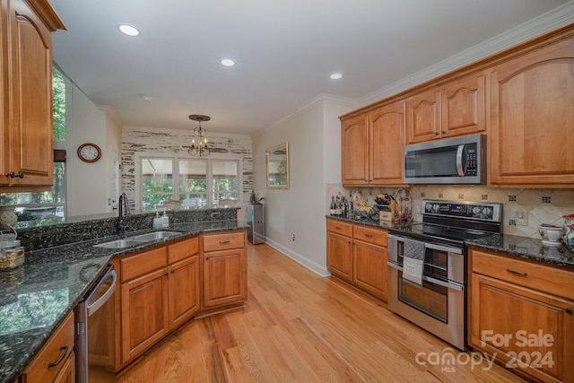 kitchen with sink, hanging light fixtures, light wood-type flooring, appliances with stainless steel finishes, and ornamental molding