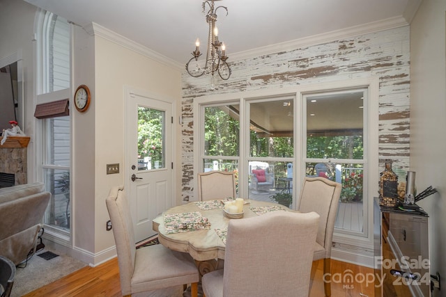 dining room featuring a fireplace, hardwood / wood-style flooring, a chandelier, and ornamental molding