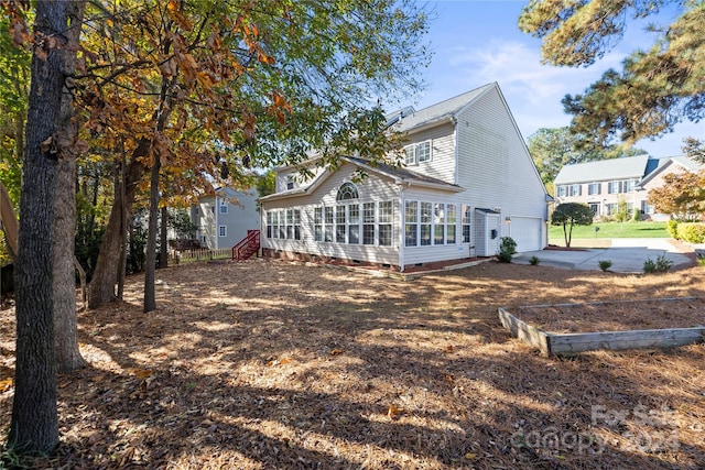 rear view of house featuring a sunroom and a garage