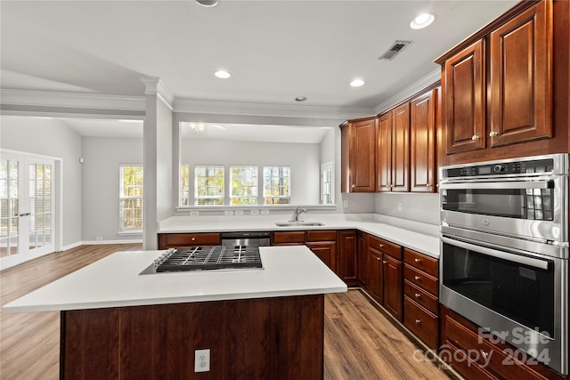 kitchen with appliances with stainless steel finishes, light wood-type flooring, a center island, and a healthy amount of sunlight