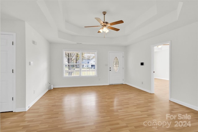 entrance foyer featuring a raised ceiling, ceiling fan, and light hardwood / wood-style floors