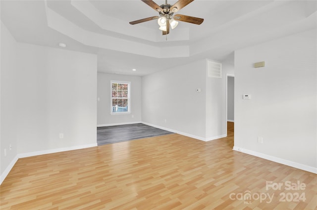 spare room featuring ceiling fan, a tray ceiling, and light hardwood / wood-style flooring