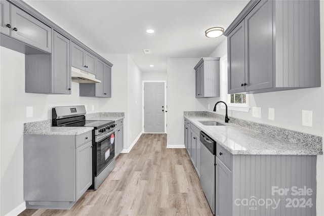 kitchen with gray cabinetry, sink, light hardwood / wood-style floors, and appliances with stainless steel finishes